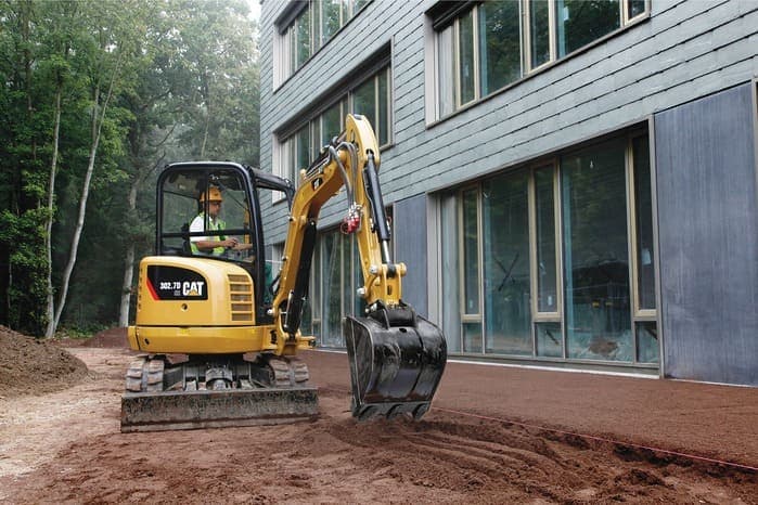 Mini-pelle en travaux de terrassement devant un bâtiment